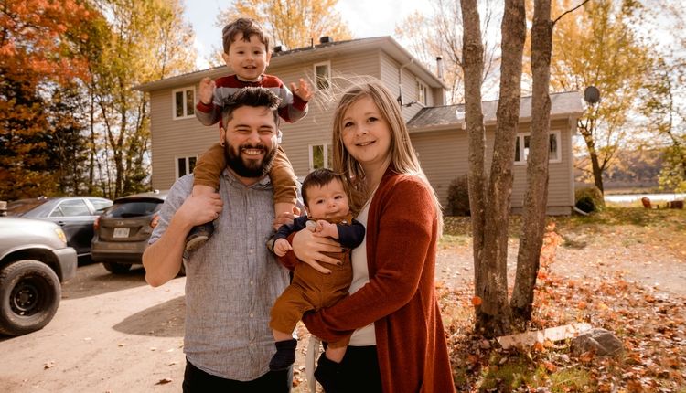 Smiling family in front of a house